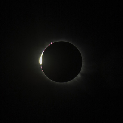 Justo antes de que comience la totalidad, las únicas partes de la brillante superficie del Sol que aún no están cubiertas por la Luna son aquellas que se asoman a través de los valles profundos del borde lunar en avance (el limbo). Vistas a través de filtros solares seguros, aparecen como un arco de puntos brillantes. Estos se denominan Perlas de Baily, en honor al astrónomo inglés Francis Baily, quien los describió por primera vez durante un eclipse solar en 1836. Desaparecen uno tras otro a medida que la Luna continúa su avance. Su posterior reaparición, cuando la Luna comienza a retirarse, marca el final de la totalidad. También visibles al inicio y al final de la totalidad son brillantes arcos rojos, bucles y chorros de gas caliente. Llamados protuberancias solares, se originan en la cromosfera —la delgada capa media de la atmósfera del Sol— y brillan en la luz rojo rubí del hidrógeno calentado a más de 20.000 °C (36.000 °F).
